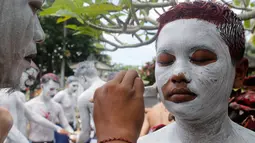 Para pemuda melukis diri mereka untuk persiapan ritual Hindu yang disebut "Grebeg" di Desa Tegallalang, Bali, Rabu (30/1). Tradisi ritual berkeliling kampung dengan riasan tubuh warna-warni itu dipercaya sebagai penangkal Roh jahat. (AP/Firdia Lisnawati)