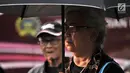 Seorang ibu yang tergabung dalam Jaringan Solidaritas Korban untuk Keadilan (JSKK) mengenakan pakaian dan payung hitam saat mengikuti Aksi Kamisan di depan Istana Negara, Jakarta, Kamis (2/8). (Merdeka.com/Iqbal Nugroho)