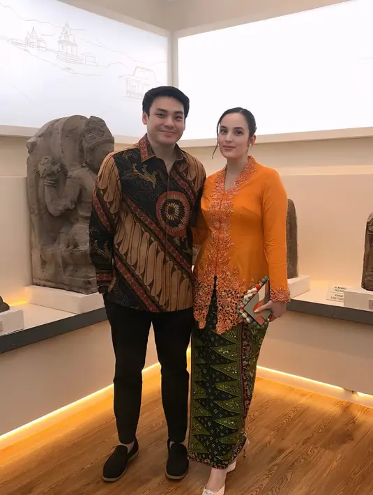 Ditemani sang suami, Chelsea Islan tampil fresh dengan kebaya encim orange. Dipadu dengan kain Batik hijau dan tas mini multiwarna [@chelseaislan]