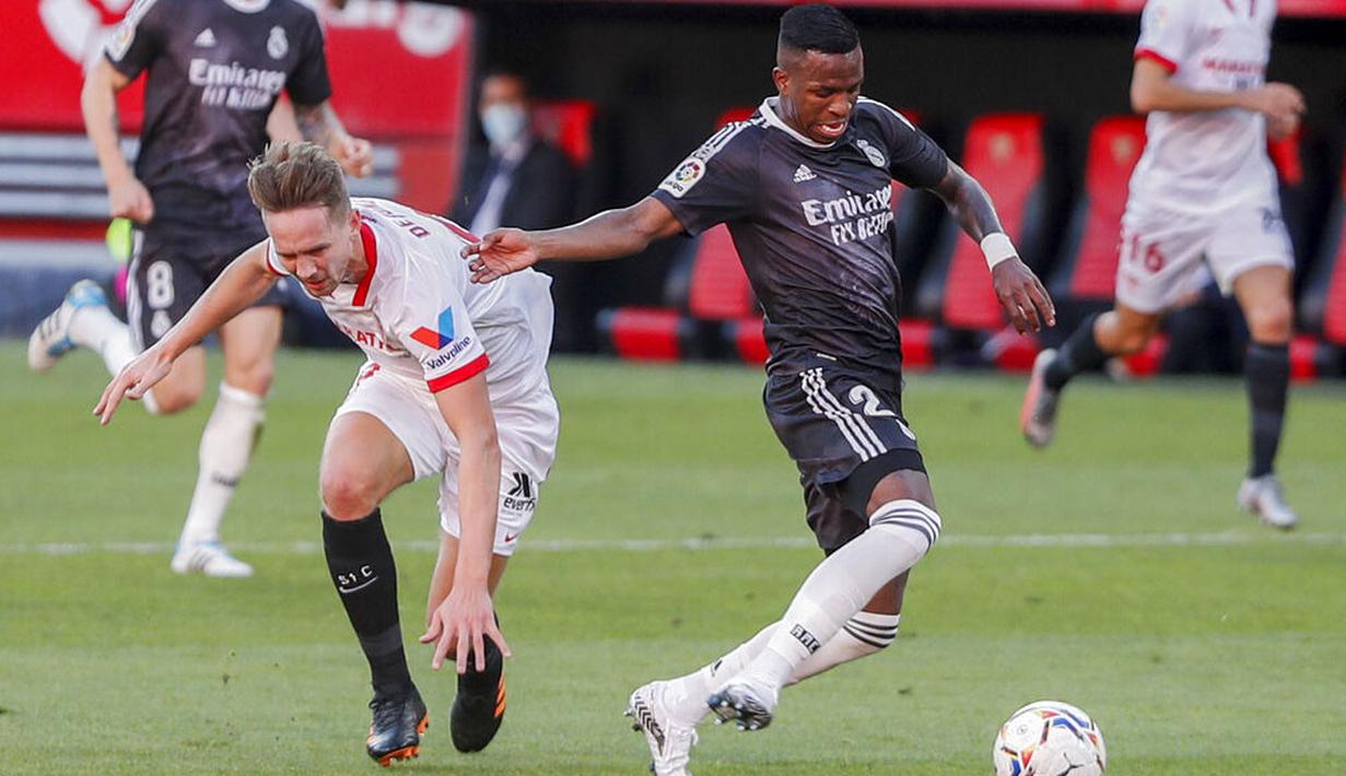 Penyerang Real Madrid, Vinicius Junior, berebut bola dengan pemain Sevilla, Luuk de Jong, pada laga Liga Spanyol di Stadion Ramon Sanchez Pizjuan, Minggu (6/12/2020). Real Madrid menang dengan skor 1-0. (AP/Angel Fernandez)