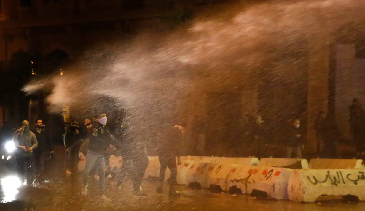 Demonstran antipemerintah disemprot air saat bentrok dengan polisi antihuru-hara dalam demonstrasi menentang pemerintahan baru dekat Parliament Square, Beirut, Lebanon, Rabu (22/1/2020). Demonstrasi dan kekerasan terus berlanjut kendati Lebanon telah mengumumkan kabinet baru. (AP Photo/Hussein Malla