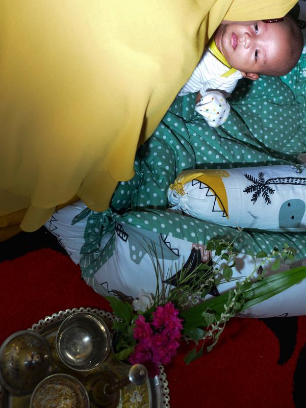 Seorang bayi menjalani ritual 'peutron tanoh aneuk' (turun tanah anak) di Banda Aceh, Aceh, Senin (15/7/2019). Ritual turun tanah anak telah menjadi tradisi sakral bagi masyarakat Aceh yang dilaksanakan pada saat bayi berusia 44 hari. (CHAIDEER MAHYUDDIN / AFP)