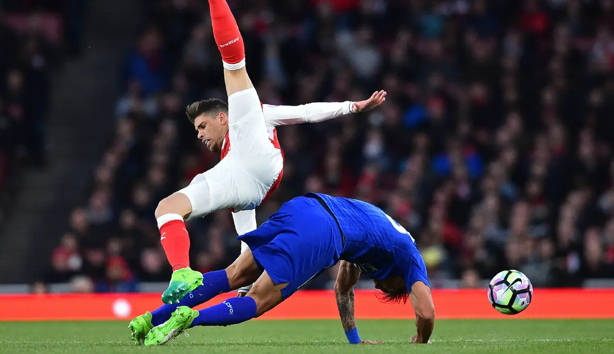 Striker Leicester, Leonardo Ulloa, terjatuh saat berebut bola dengan bek Arsenal, Gabriel, pada laga Premier League di Stadion Emirates, London, Rabu (26/4/2017). Arsenal menang 1-0 atas Leicester. (AFP/Glyn Kirk)