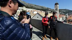 Wisatawan berfoto di benteng kota tua Dubrovnik di Kroasia pada 28 Maret 2019. Kota tua Dubrovnik  yang telah dianugerahi UNESCO sebagai warisan dunia menjadi salah satu hal yang menjadi daya tarik wisatawan untuk terbang atau berlayar ke kota yang dikelilingi pulau ini. (Denis LOVROVIC / AFP)