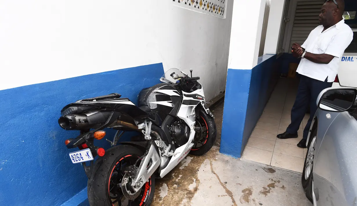 Seorang pria melihat motor yang dikendarai Germaine Mason di kantor polisi Kingston, Jamaika (20/4). Atlet cabang atletik Inggris ini dikabarkan tewas akibat kecelakaan setelah kehilangan kendali mengemudikan motornya. (AFP Photo/Jewel Samad) 