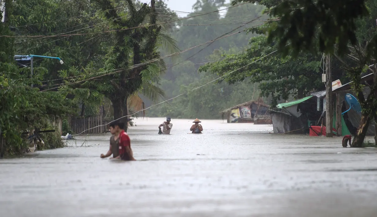 Warga menerobos banjir yang merendam di kecamatan Mawlamyine, negara bagian Mon, Myanmar (18/6). Beberapa wilayah di negara bagian Mon, menghadapi banjir akibat hujan deras sejak akhir pekan lalu. (AFP PHOTO / Ye Aung Thu)