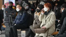 Orang-orang yang memakai masker duduk di bangku di stasiun kereta Seoul, setelah Korea Selatan mencabut mandat masker dalam ruangan, Senin (30/1/2023). Kewajiban itu diberlakukan selama lebih dari 2 tahun dan diakhiri karena kasus COVID-19 yang terus menurun. (Jung Yeon-je / AFP)