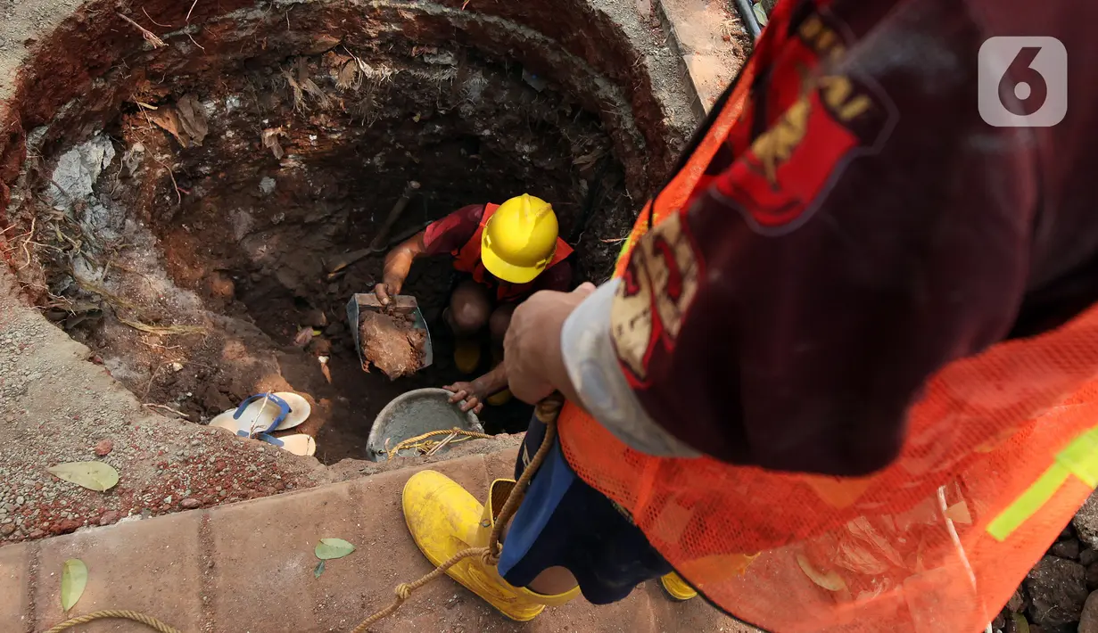 Pekerja saat membuat lubang untuk sumur rasapan di Jalan Kebon Jeruk, Jakarta Barat, Jumat (15/10/2021). Hingga saat ini, Pemprov DKI Jakarta sudah membuat sumur resapan di 6.233 titik. (Liputan6.com/Johan Tallo)