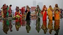 Umat Hindu India berdoa sambil berdiri di perairan Sungai Yamuna selama Festival Chhath di New Delhi, Selasa (13/11). Festival Hindu kuno ini dilakukan sebagai bentuk terima kasih kepada Dewa Matahari yang menopang kehidupan di bumi. (AP/Altaf Qadri)