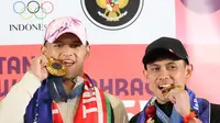 Dua atlet Indonesia peraih medali emas di Olimpiade 2024 Paris Rizki Juniansyah (kiri) dan Veddriq Leonardo (kanan) berpose menggigit medali emasi usai tiba di Bandara Internasional Soekarno-Hatta, Tangerang, Selasa (13/8/2024) (Abdul Aziz/Bola.com).&nbsp;