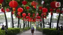 Warga melintas di bawah lampu lampion merah yang terpasang di trotoar kawasan jalan Jenderal Sudirman, Jakarta, Kamis (15/1/2025). (Liputan6.com/Angga Yuniar)