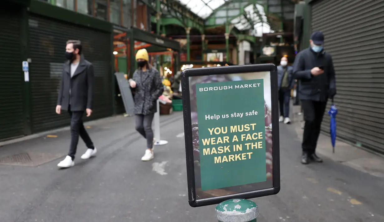 Tanda yang memberitahu pengunjung untuk memakai masker dipasang di pintu masuk Borough Market di London selatan selama penguncian nasional (lockdown) ketiga Inggris, Selasa (12/1/2021). Borough Market menjadi tempat pertama yang mewajibkan pemakaian masker di luar ruangan. (AP Photo/Alastair Grant)
