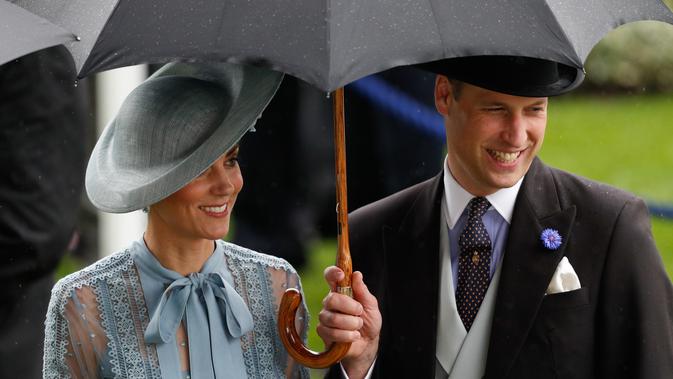 Duchess of Cambridge Kate Middleton bersama suaminya Duke of Cambridge Pangeran William mengenakan payung saat menghadiri ajang pacuan kuda Royal Ascot di Ascot, Inggris, Selasa (18/6/2019). (ADRIAN DENNIS/AFP)