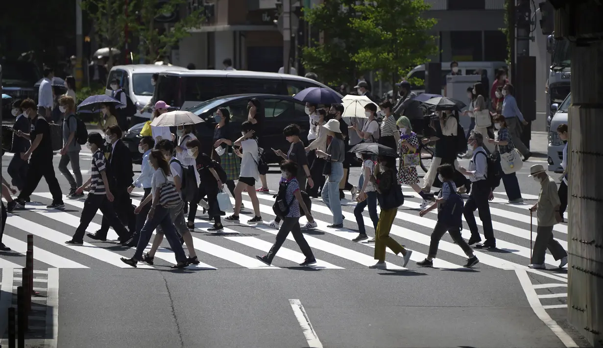 Orang-orang berjalan di atas penyeberangan pejalan kaki di bawah terik matahari di Tokyo, Senin (30/5/2022). Cuaca panas pada hari Senin telah ditetapkan dengan suhu naik lebih dari 27 derajat Celcius (80,6 derajat Fahrenheit) di Tokyo, menurut Badan Meteorologi Jepang. (AP Photo/Eugene Hoshiko)