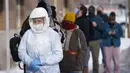 Petugas pengujian COVID-19 Departemen Kesehatan Salt Lake County berjalan melewati antrean warga di luar Departemen Kesehatan Salt Lake County, Salt Lake City, Utah, Amerika Serikat, 28 Desember 2021. Saham maskapai-maskapai AS anjlok akibat lonjakan kasus COVID-19. (AP Photo/Rick Bowmer)