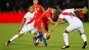 Penyerang Chile, Alexis Sanchez (tengah) berusaha melewati dua pemain Peru pada Kualifikasi Piala Dunia 2018 di National Stadium, Santiago, Chile (11/10).  Chile menang atas Peru dengan skor 2-1. (REUTERS/Rodrigo Garrido)