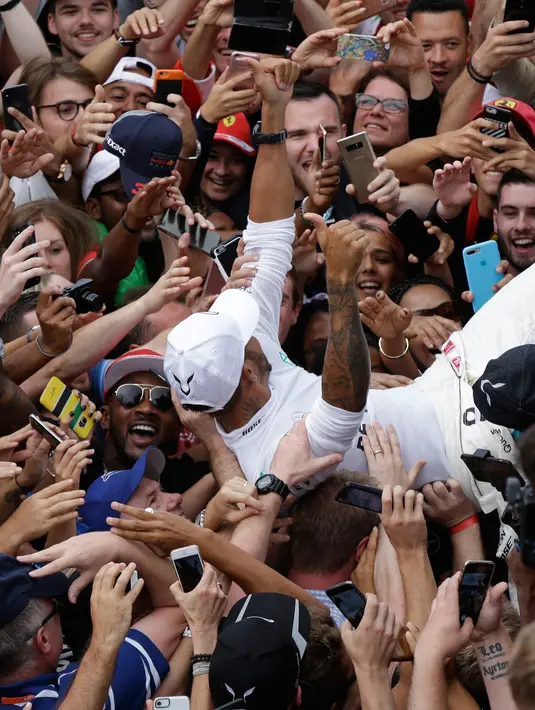 Lewis Hamilton berselebrasi bersama pendukungnya usai meraih kemenangan GP Italia di Sirkuit Monza di Monza, (2/9). Hamilton berhasil menang di GP Italia 2018 dengan catatan waktu terbaik 1 jam 16 menit 54,484 detik. (AP Photo/Luca Bruno)