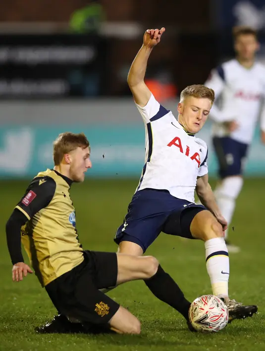 Gelandang Marine, James Barrigan (kiri) bersaing dengan gelandang Tottenham Hotspur, Harvey White dalam babak ketiga Piala FA di Rossett Park, Crosby, Inggris, Minggu (10/1/2021). Tottenham Hotspur tanpa ampun menggilas tim semi-profesional, Marine dengan 5-0.  (Clive Brunskill / POOL / AFP)