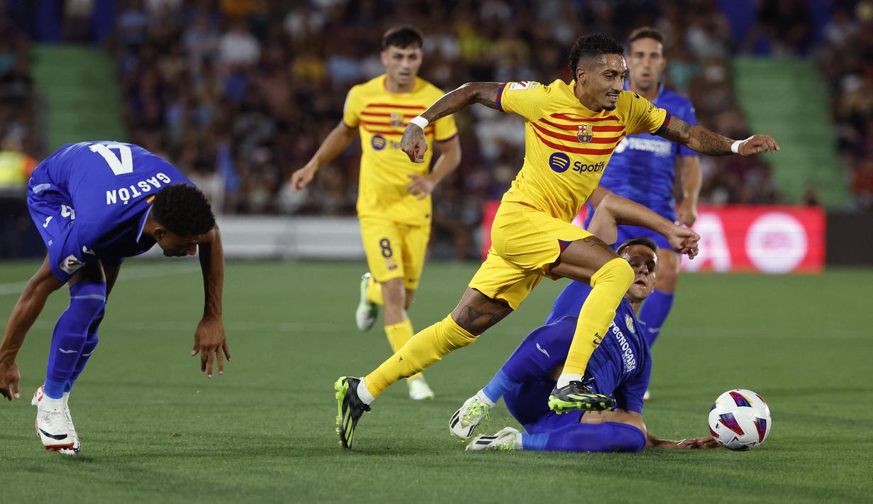 Pemain Barcelona, Raphinha (kanan) berusaha melewati pemain Getafe pada laga pekan pertama Liga Spanyol 2023/2024 melawan Getafe di Coliseum Alfonso Perez Stadium, Getafe, Spanyol, 14 Agustus 2023 WIB. (AFP/Javier Soriano)