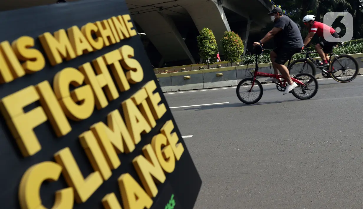 Pesepeda melintas di sisi media kampanye lingkungan aktivis Greenpeace dan Bike2Work di Jalan Jenderal Sudirman, Jakarta, Minggu (5/6/2022). Aksi untuk mengkampanyekan penggunaan sepeda sebagai kendaraan ramah lingkungan dan solusi pembangunan Jakarta Kota Ramah Pesepeda. (Liputan6.com/Helmi Fithriansyah)