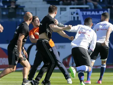 Seorang suporter masuk ke lapangan dan menyerang pemain Lyon yang sedang melakukan pemanasan di Armand Cesari stadium, Bastia, (16/4/2017). Laga ini akhirnya dihentikan LFP. (AFP/Pascal Pochard-Casabianca)