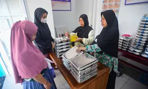 Ibu hamil mengambil makan bergizi gratis (MBG) untuk dikonsumsi di rumah di Posyandu kawasan Limo, Depok, Jawa Barat, Selasa (14/7/2025).