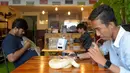 Foto yang diambil pada 18 Agustus 2018 menunjukkan pelanggan menikmati minuman sambil bermain dengan ular piton dan kalajengking di Reptile Cafe, Phnom Penh, Kamboja. Reptil yang ada di kafe ini didatangkan langsung dari Thailand. (AFP/TANG CHHIN Sothy)