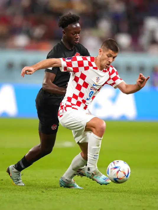 Pemain Kroasia Andrej Kramaric (9) menggiring bola di depan pemain Kanada Ismael Kone (15) pada pertandingan sepak bola Grup F Piala Dunia 2022 di Stadion Internasional Khalifa, Al Rayyan, Qatar, 27 November 2022. Kroasia mengalahkan Kanada dengan skor 4-1. (Nathan Denette/The Canadian Press via AP)