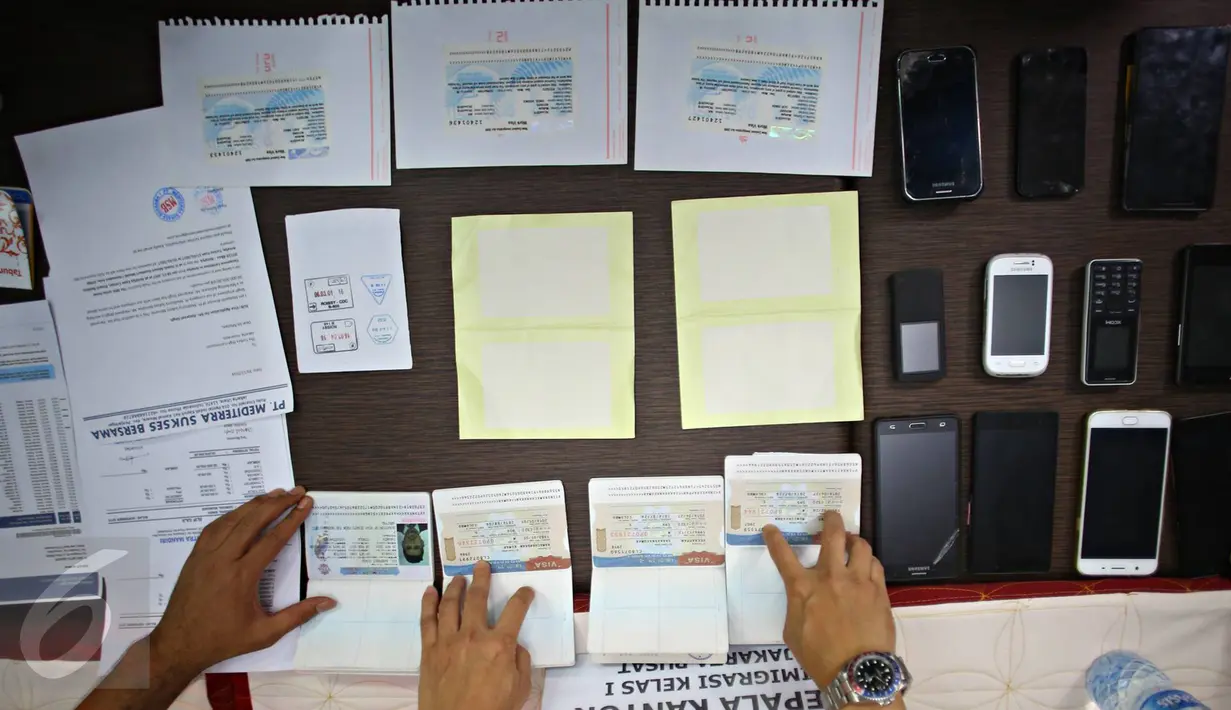 Petugas imigrasi menunjukan barang bukti dan tersangka saat rilis sindikat internasional pemalsuan dokumen keimigrasian di Kantor Imigrasi Jakarta Pusat, Rabu, (18/1). (Liputan6.com/Immanuel Antonius)