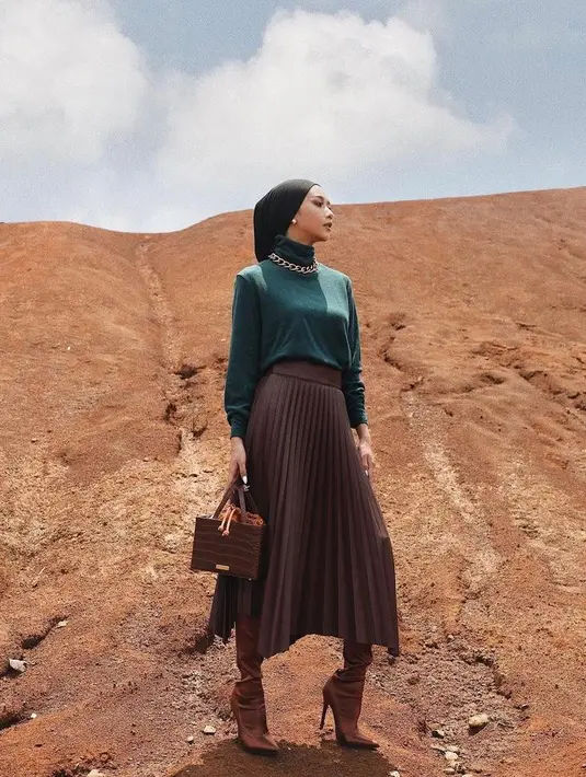 Untuk look yang elegan, kamu bisa pilih rok plisket material leather. Agar makin chic, padukan dengan turtleneck warna hijau emerald dan chain necklace (Instagram/viratandia).