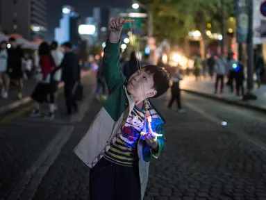 Seorang anak bersiap meluncurkan mainannya selama perayaan Chuseok di sebuah jalan di Seoul (5/10). Chuseok merupakan festival panen tahunan dan hari libur nasional selama seminggu di Korea Selatan. (AFP Photo/Ed Jones)