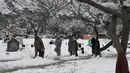 Sejumlah orang berjalan melewati makam usai hujan salju lebat di Quetta, Pakistan, Senin (13/1/2020). Cuaca buruk berupa hujan salju lebat, hujan, dan banjir bandang melanda Pakistan dan Afghanistan. (Banaras KHAN/AFP)