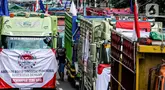 Salah satu peserta aksi terlihat di antara truk-truk saat unjuk rasa terkait Rancangan Undang Undang (RUU) nol kelebihan muatan dan dimensi atau Zero Over Dimension Over Load (ODOL) memasang spanduk di Jalan Medan Merdeka Selatan, Jakarta, Rabu (2/7/2025). (Liputan6.com/Herman Zakharia)