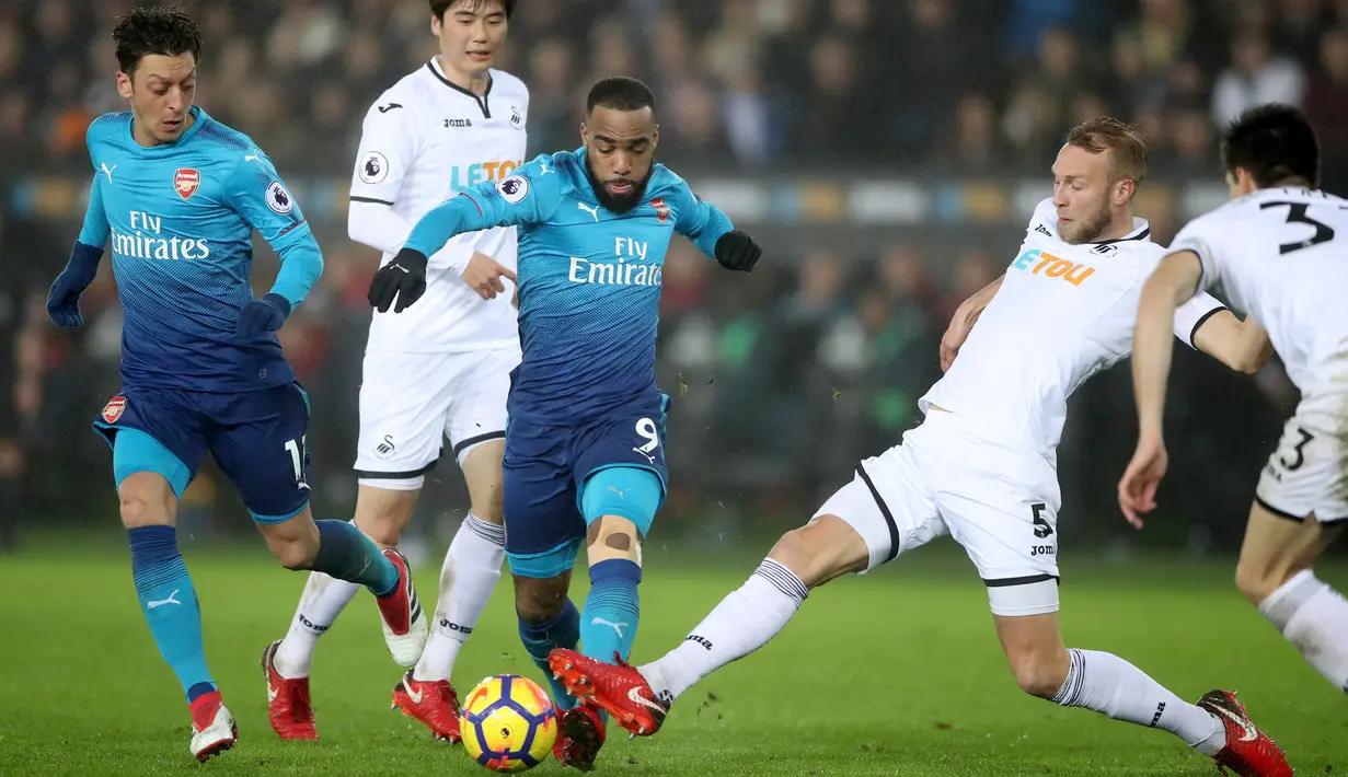 Pemain Arsenal, Alexandre Lacazette berebut bola dengan pemain Swansea City Mike van der Hoorn dalam laga pekan ke-25 Premier League  di Liberty Stadium, Selasa (30/1). Arsenal secara mengejutkan takluk dari Swansea City 1-3. (Nick Potts/PA via AP)
