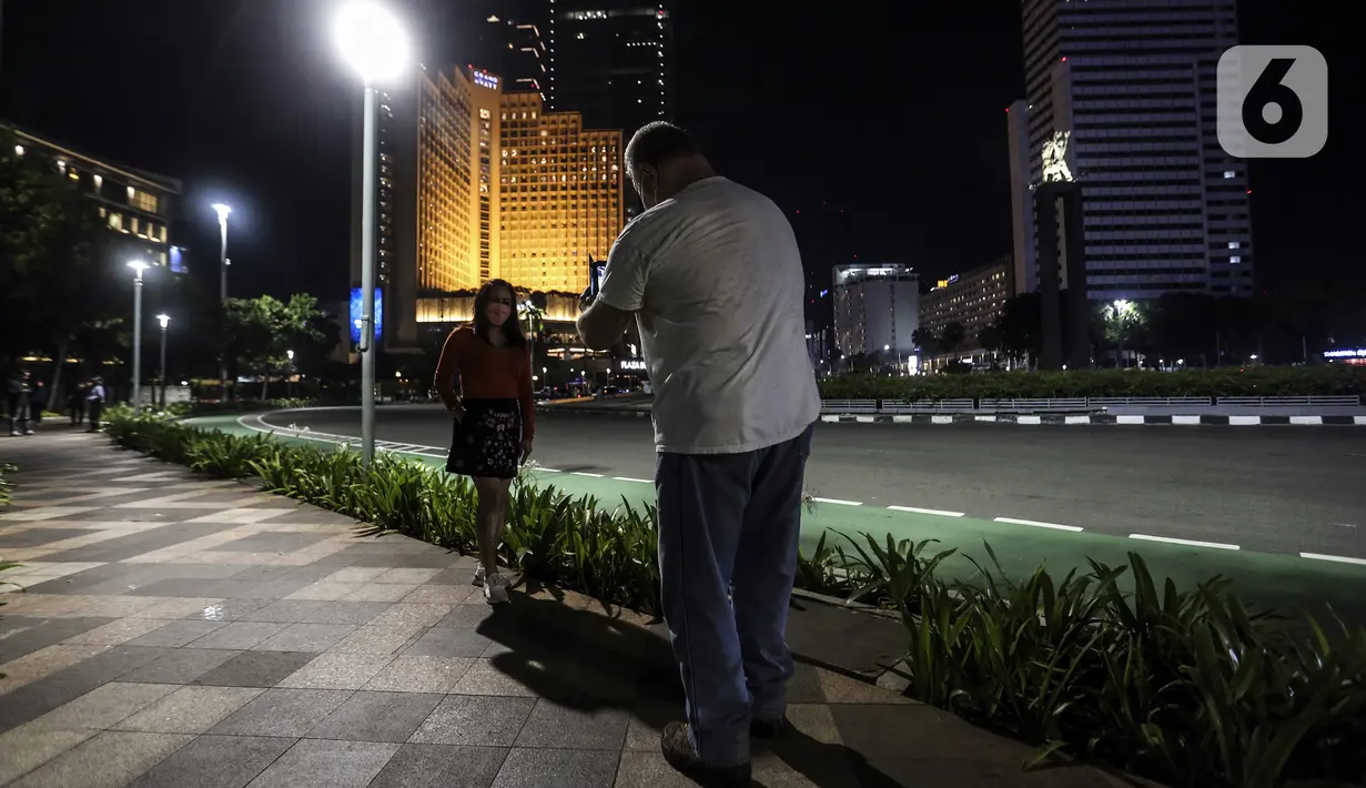 Warga berpose untuk difoto saat perayaan malam Tahun Baru di Jakarta, Jumat (31/12/2021). Polda Metro Jaya melakukan pengendalian mobilitas Crowd Free Night (malam bebas keramaian) dengan membubarkan warga yang nekat keluar rumah dan tidak mematuhi aturan. (Liputan6.com/Johan Tallo)