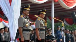Jenderal Badrodin Haiti dan Jenderal Tito Karnavian berdiri di atas mimbar dalam upacara sertijab Kapolri di Stadion PTIK, Jakarta, Kamis (14/7). Badrodin Haiti resmi menyerahkan tongkat komando Kapolri kepada Tito Karnavian. (Liputan6.com/Helmi Afandi)