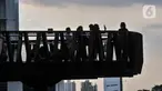 Warga berfoto saat ngabuburit di JPO Pinisi Pinisi Karet-Sudirman, Jakarta Pusat, Senin (4/4/2022). JPO Pinisi kini menjadi destinasi baru warga Jakarta untuk menunggu waktu berbuka puasa atau ngabuburit sambil menikmati suasana perkotaan. (merdeka.com/Iqbal S. Nugroho)
