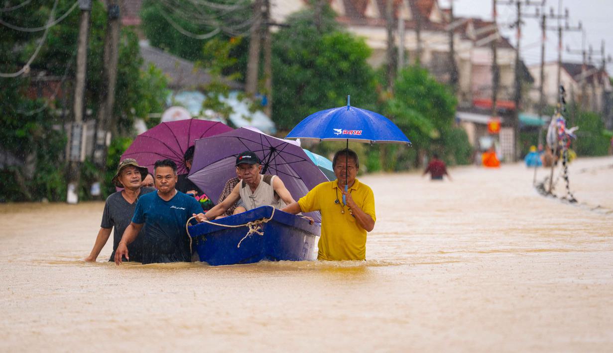 Ketinggian air di sejumlah distrik dilaporkan mencapai dua meter. Tampak dalam foto, warga berjalan melewati banjir sementara warga dievakuasi dengan perahu di Hat Yai, Provinsi Songkhla, Thailand selatan, pada Selasa 25 November 2025. (Arnun Chonmahatrakool/THAI NEWS PIX/AFP)