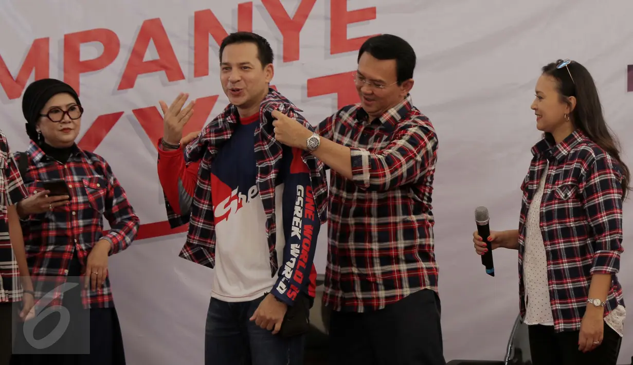 Cagub DKI Jakarta Basuki Tjahaja Purnama atau Ahok memakaikan kemeja kotak-kotak ke artis peran Ari Wibowo disaksikan Ira Wibowo, sebelum menyampaikan dukungan mereka ke Ahok-Djarot di Rumah Lembang, Jakarta, Kamis (24/11). (Liputan6.com/Gempur M Surya)