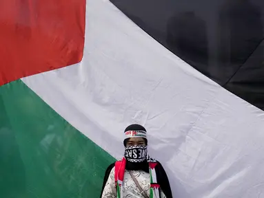 Seorang perempuan berdiri di depan bendera besar Palestina saat aksi bela Palestina, di Monumen Nasional atau Monas, Jakarta Pusat, Minggu (5/11/2023). (AP Photo/Dita Alangkara)