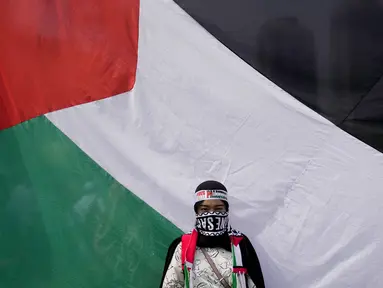 Seorang perempuan berdiri di depan bendera besar Palestina saat aksi bela Palestina, di Monumen Nasional atau Monas, Jakarta Pusat, Minggu (5/11/2023). (AP Photo/Dita Alangkara)