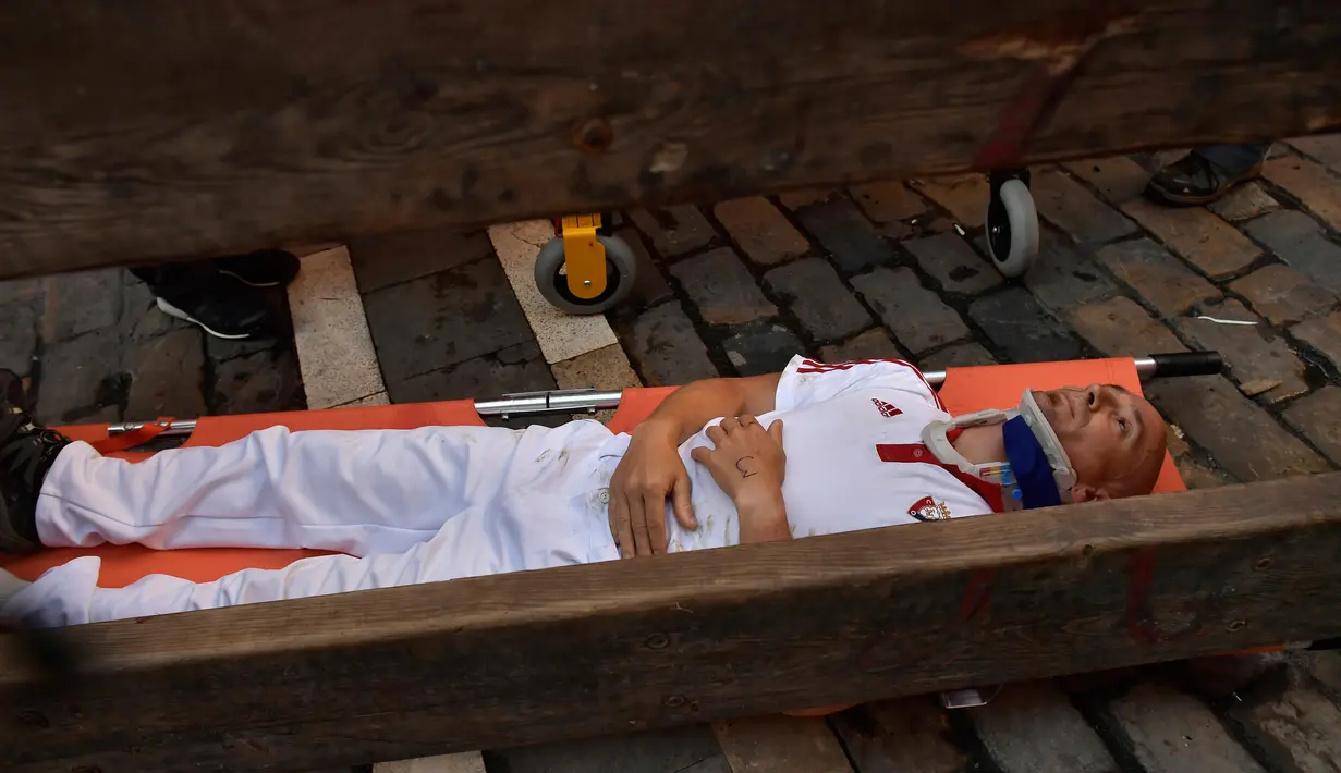 Seorang peserta terluka usai diseruduk banteng dalam Festival San Fermin di Pamplona, Spanyol, Senin (9/7). (AP Photo/Alvaro Barrientos)