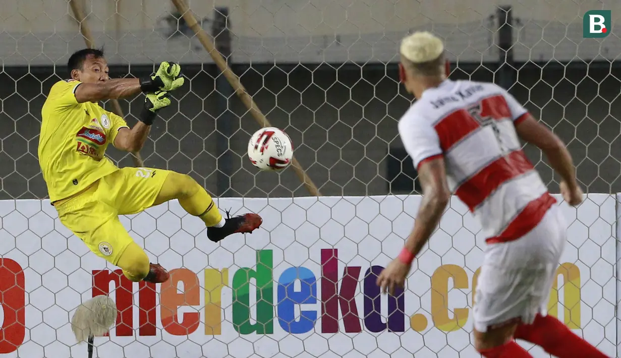 Kiper PSS Sleman, Ega Rizky menghalau tendangan dari bek Madura United, Jaimerson Xavier dalam laga Grup C Piala Menpora 2021 di Stadion Si Jalak Harupat, Bandung, Selasa (23/3/2021). PSS Sleman kalah 1-2 dari Madura United. (Bola.com/M Iqbal Ichsan)