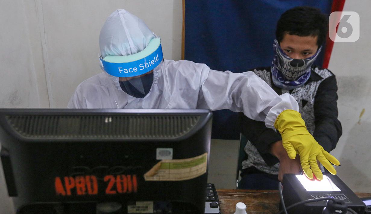 Petugas Dukcapil lengkap dengan APD memindai sidik jari KTP Elektronik di Kecamatan Pamulang, Tangerang Selatan, Senin (15/6/2020) Dukcapil Tangsel membuka layanan rekaman E-KTP jelang Pilkada dengan menerapkan ketentuan New Normal guna mencegah penyebaran Virus Covid-19. (Liputan6.com/Fery Pradolo)