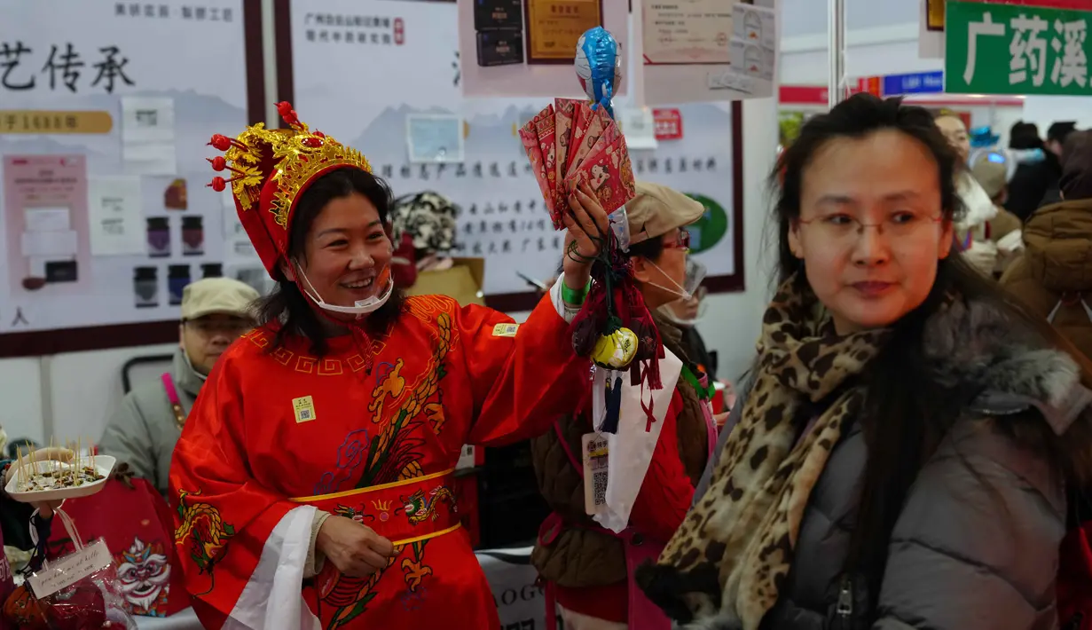 Seorang pekerja mengenakan kostum dewa keberuntungan untuk menarik pelanggan ke kiosnya saat bazar menyambut Tahun Baru Imlek di Beijing, China, Minggu 1 Februari 2026. Jelang perayaan Tahun Baru Imlek di China, suasana sibuk dan meriah mendominasi. (AP Photo/Andy Wong)