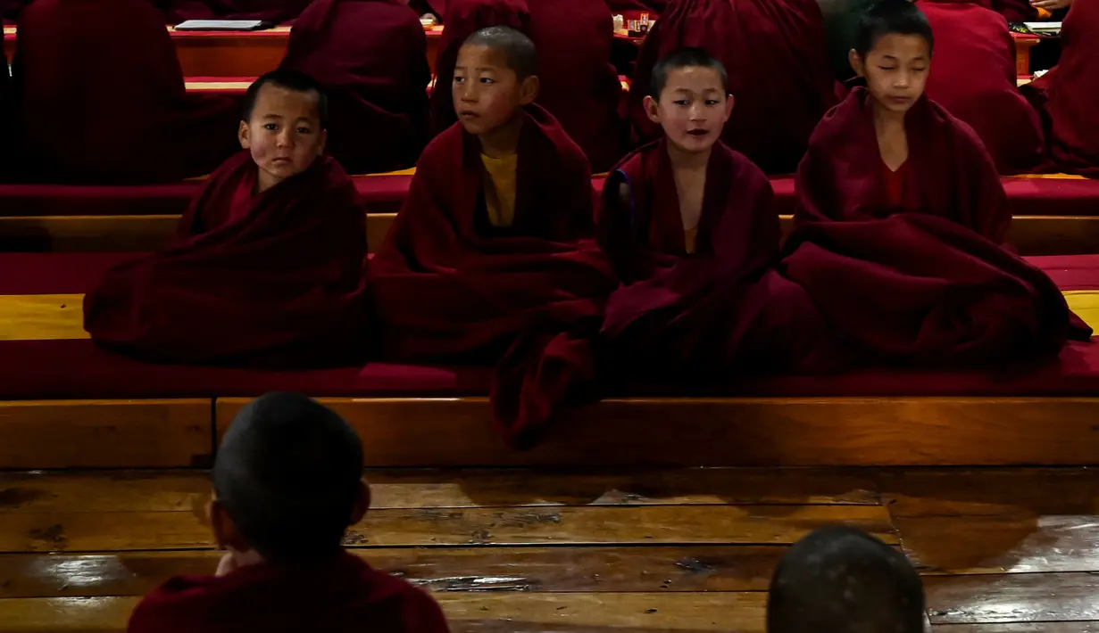 Biksu Buddha muda memberi isyarat saat mereka melakukan doa pagi. Jika seorang bhikkhu ingin meninggalkan vihara, dikenakan hukuman berat. (AFP/Arun Sankar)
