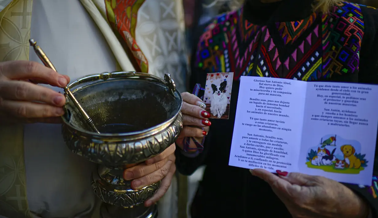 Seorang wanita menunjukkan foto hewan peliharaannya sambil menunggu untuk diberkati saat pesta Santo Antonius di Pamplona, Spanyol, 17 Januari 2022. Pesta ini dirayakan setiap tahun dan orang-orang membawa hewan peliharaan mereka ke gereja untuk diberkati. (AP Photo/Alvaro Barrientos)