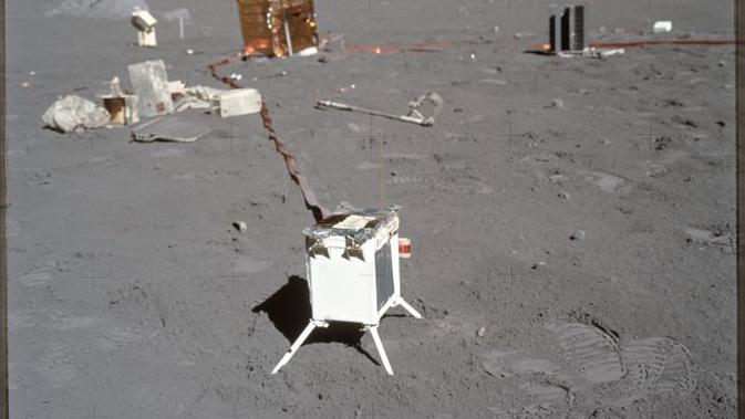 Sebuah foto yang diambil selama Apollo 17 menunjukkan percobaan sains di latar depan dan latar belakang dengan tumpukan puing-puing, termasuk pembungkus percobaan dan sampul di sebelah kiri. (NASA)