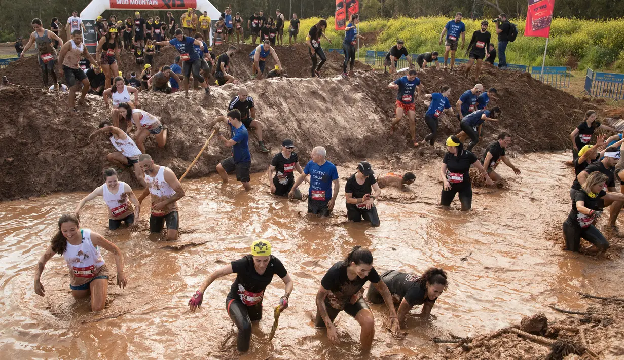 Sejumlah peserta tercebur di kolam lumpur saat memulai perlombaan Mud Day di Tel Aviv, Israel (16/3). Sekitar 5.000 orang ikut berpartisipasi dalam lomba Hari Lumpur di Tel Aviv ini. (AFP Photo/Jack Guez)