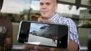 Seorang penumpang menunjukkan gambar dari pesawat milik maskapai Dynamic International Airways yang terbakar saat akan lepas landas di Bandara Fort Lauderdale, Florida, Kamis (29/10). 15 orang terluka akibat kejadian tersebut (Joe Raedle/Getty Images/AFP)